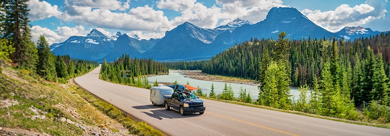 Truck with camper driving down the road.